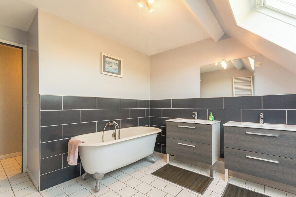 A modern bathroom with a freestanding bathtub, two vanity sinks, and a large mirror.