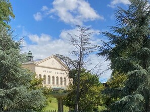 Ein prachtvolles Gebäude im klassischen Stil, umgeben von üppigem Grün und blauem Himmel.