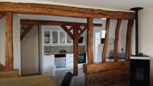 Eine rustikale Küche mit freiliegenden Holzbalken, weißen Schränken und einem schwarzen Herd.