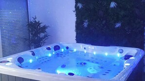 Ein Whirlpool mit integrierter Beleuchtung, umgeben von Zimmerpflanzen.
