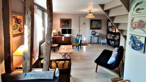 Una sala de estar acogedora con una viga de madera, un comedor y una escalera que sube a otro nivel.