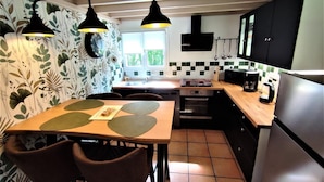 Una cocina compacta con una mesa, sillas, estufa, fregadero y refrigerador.