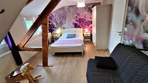 Une chambre à coucher avec un lit, une table de chevet, une commode, un cheval à bascule et un canapé à motifs.