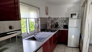 A kitchen with a large island, a microwave, and a refrigerator. - Gîtes de France® - Le Petit Gîte (ERMENOUVILLE)