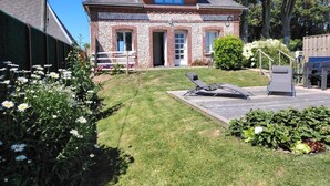 Ein zweistöckiges Haus mit Steinaußenwand, einer Haustür und einer kleinen Veranda mit einer Bank.
