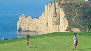Ein Golfplatz mit einer hohen Klippe im Hintergrund.