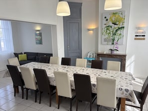 Een eetruimte met een tafel gedekt voor 8 personen, omringd door stoelen, een bank en een kinderstoel.