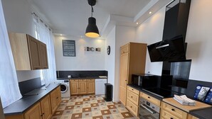 A modern kitchen with wooden cabinets, a black countertop, a microwave, and a built-in oven. - Gîtes de France® - Gîte du Loup Vert (JUMIEGES)