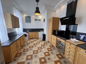 Une cuisine moderne avec des meubles en bois, un plan de travail noir, un four à micro-ondes et un four encastré.