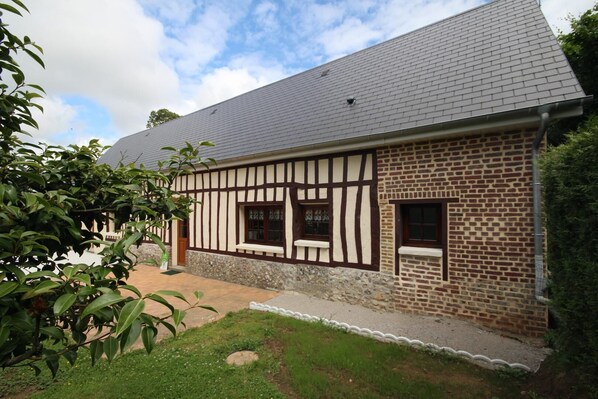 A traditional half-timbered house with a sloped roof, a stone foundation, and a small front porch.