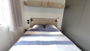Una cama con colcha a rayas, cabecera de madera y dos lámparas de noche.
