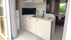 Una cocina compacta con estufa integrada, un lavamanos y un pequeño comedor con mesa y sillas.