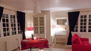 Een eethoek met een tafel gedekt voor twee personen, een rode tafelkleed en een kaars op tafel.
