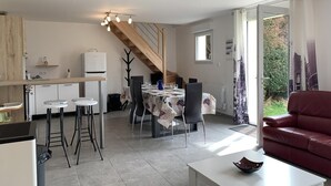 Una cuina moderna amb zona de menjador, escala i sofà de pell vermell.