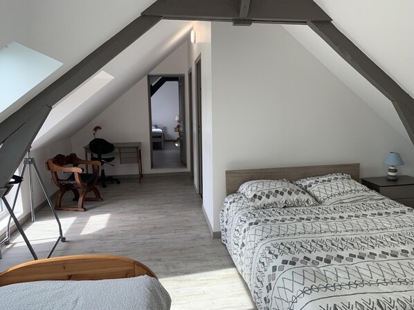 Une chambre mansardée chaleureuse avec un plafond en pente, un lit en bois, un bureau et une chaise.