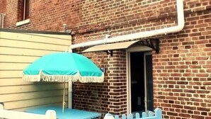 A brick building with a blue outdoor seating area and a white picket fence. - Gîtes de France® - La Mouette (LE TREPORT)