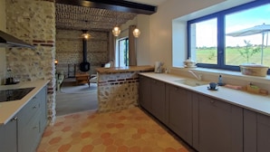 A modern kitchen with a stone wall, a built-in stove, and a large window offering a view of the outdoors.