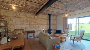 A cozy living room with a brick wall, wooden furniture, a fireplace, and a view of the outdoors.