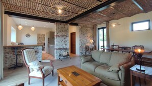 A spacious living area with a brick ceiling, a sofa, a wooden coffee table, and a dining table with chairs.