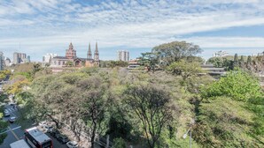 Une vue urbaine mettant en valeur une église imposante, reconnaissable à ses deux flèches jumelles, entourée d’arbres et d’immeubles modernes.