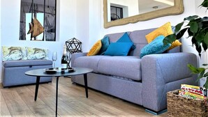 A living room with a grey sofa, a round coffee table, and a large mirror.
