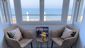 A room with two beige armchairs, a small round table, and a poster on the wall.