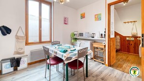 A cozy room with a dining table, chairs, a microwave, and a small kitchenette. - Gîtes de France® - Flab'Zen (CRIEL SUR MER)
