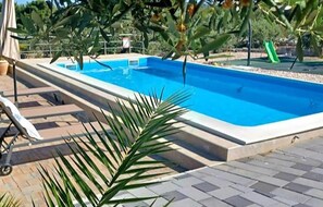 Relax by the pool surrounded by lush greenery and a children's play area.