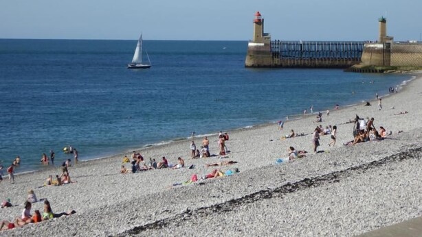 A beach with people sunbathing and a sailboat in the water. - Gîtes de France® - Bayen's Family (FECAMP)