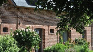 Ein Ziegelgebäude mit Garten, einschließlich eines rosa Pflanzkübels und verschiedenen Pflanzen.