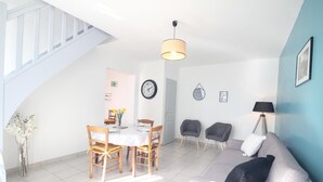 Una sala de estar moderna con comedor, una escalera y un reloj en la pared.