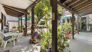 An outdoor patio with wooden beams, potted plants, and a table with chairs.