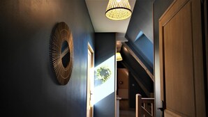 Ein Flur mit blauer Wand, einer Holztür und einer Treppe, die zu einer oberen Ebene führt.