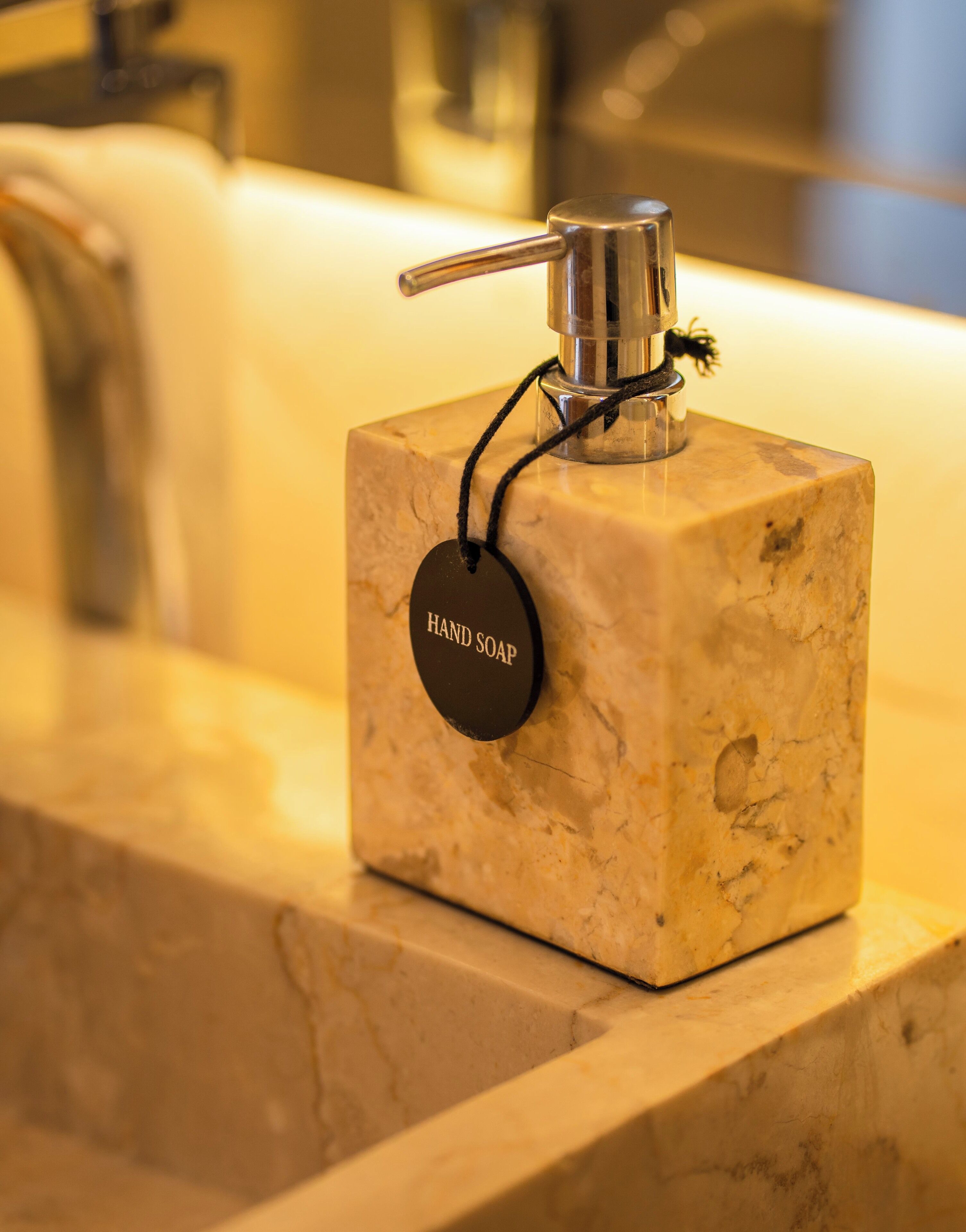 Un distributeur de savon liquide sur un comptoir en marbre dans une salle de bain.