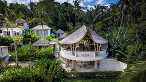 Um resort com um gazebo central, rodeado por vegetação exuberante e palmeiras.