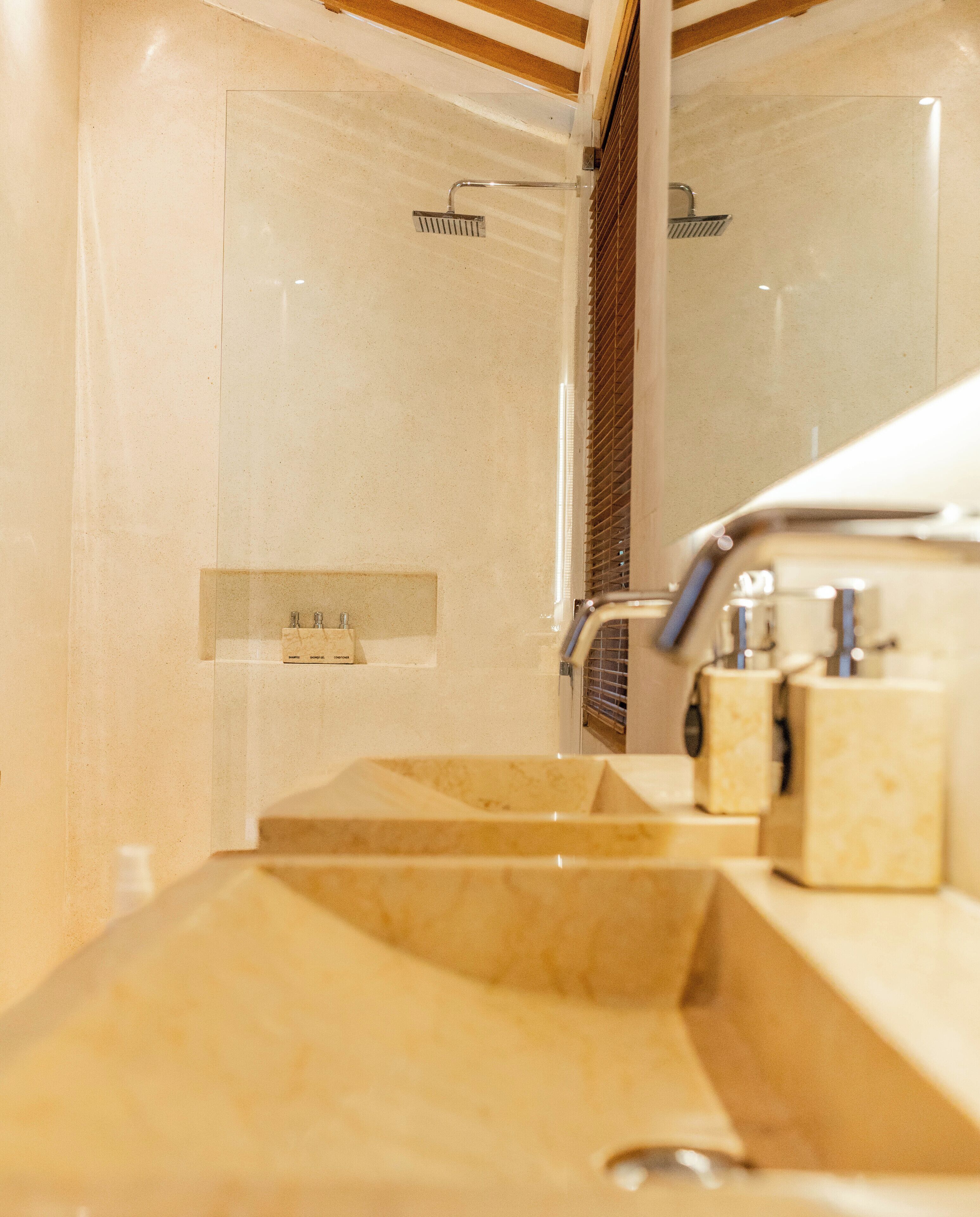 Un baño con un lavabo color crema, un espejo y una zona de ducha.