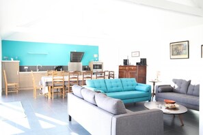 Cozy living space with a dining area, sofa, and armchair, featuring a kitchen with sink, stove, and cabinets.