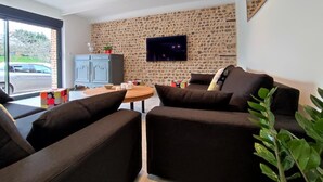 Una sala de estar moderna con una pared de piedra, un televisor de pantalla plana y un rincón de descanso acogedor.