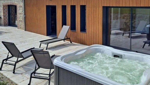 Una casa moderna con jacuzzi, sillones de descanso y un ventanal grande.