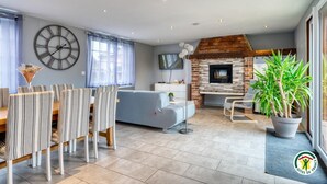 Un salon moderne comprenant un coin repas, une cheminée et une grande horloge murale.