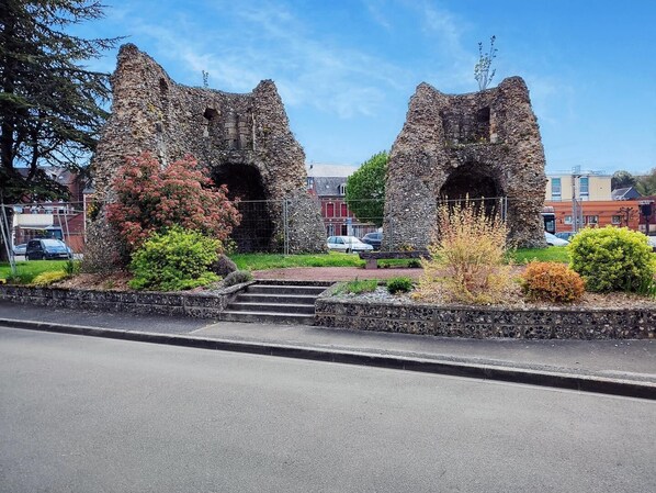 A stone structure with two arches, surrounded by landscaped gardens and a paved walkway.