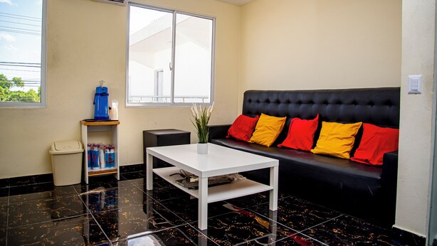 A modern living room with a black sofa, a white coffee table, and a window with blinds. - Spacious room (queen size bed) in a hotel in Punta Cana (Punta Cana)