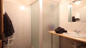 Un baño con ducha, lavamanos y espejo.
