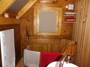 Eine Holzhütte mit spiegelndem Holzrahmen, einem Handtuchhalter und einem Regal mit Gegenständen.