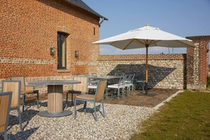 Relax on the patio with a round table and six comfortable chairs, shaded by a large umbrella.