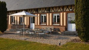 A building with a traditional half-timbered facade, large windows, and outdoor seating with umbrellas.