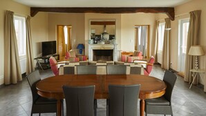 A dining area with a wooden table and chairs, a television, and a fireplace.