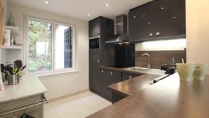 A modern kitchen with dark cabinetry, a stainless steel sink, and a window providing a view of greenery outside.