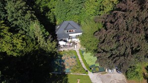 An aerial view of a house surrounded by dense forest.