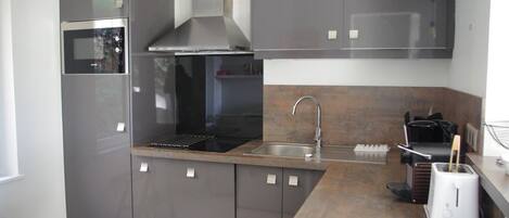 Una cucina moderna con forno integrato, pensili in acciaio inossidabile, cappa aspirante, lavello e tostapane.